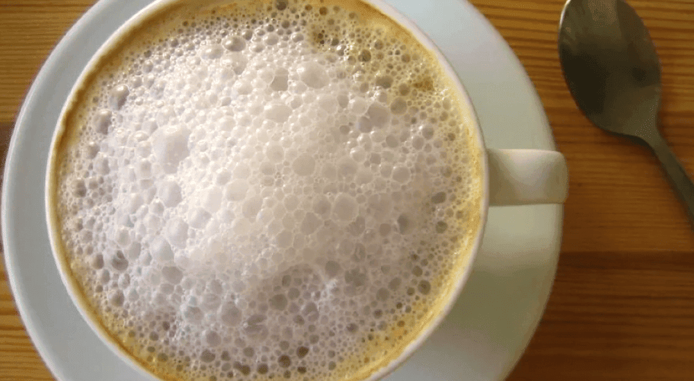 Foamed-Milk in a coffee cup on a wooden table